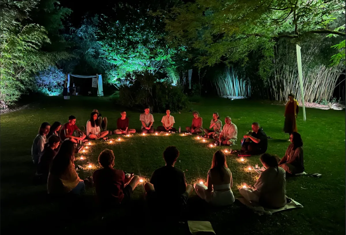 Cercle nocturne de 無我茶會 — WúWǒCháHuì au Parc aux Bambous : participantes assises en cercle sur l'herbe, bougies disposées au centre, bambous éclairés en arrière-plan.